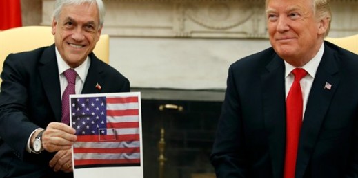 President Donald Trump, right, smiles as Chilean president Sebastian Pinera holds up a picture showing the Chilean flag at the center of the U.S. flag, in the Oval Office of the White House, in Washington, Sept. 28, 2018 (AP photo by Alex Brandon).