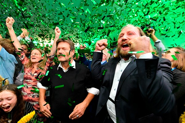 Robert Habeck, center, and Anton Hofreiter, right, leaders of the Greens, celebrate the results of the Bavaria state elections, Munich, Germany, Oct. 14, 2018 (AP photo by Kerstin Joensson).