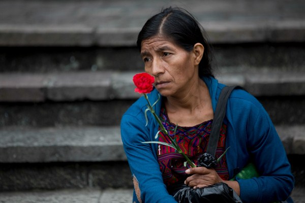 An Ixil woman holds a red carnation during a memorial ceremony for victims of Guatemala’s civil war, Guatemala City, Sept. 26, 2018 (AP photo by Moises Castillo).