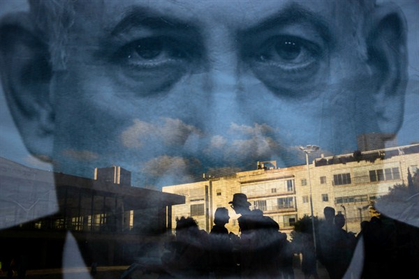 People are seen through a banner showing Israeli Prime Minister Benjamin Netanyahu during a protest against the nation-state law, Tel Aviv, Israel, July 30, 2018 (AP photo by Oded Balilty).