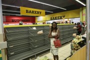 A woman walks past empty bread shelves in a shop in Harare, Zimbabwe, Oct. 9, 2018 (AP photo by Tsvangirayi Mukwazhi).