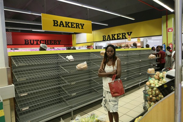 A woman walks past empty bread shelves in a shop in Harare, Zimbabwe, Oct. 9, 2018 (AP photo by Tsvangirayi Mukwazhi).