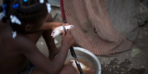 A girl removes scales from a fish in her home in Belle Anse, Haiti, May 22, 2013 (AP photo by Dieu Nalio Chery).