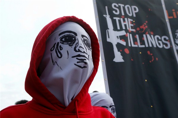 A masked protester stands next to a banner depicting thousands of victims of President Rodrigo Duterte’s war on drugs during a protest rally in Quezon city, the Philippines, July 23, 2018 (AP photo by Bullit Marquez).