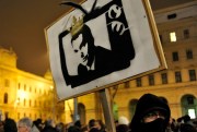 A Hungarian man holds a banner depicting Prime Minister Viktor Orban as a king on TV during a demonstration against a government media law, Budapest, Hungary, Jan. 27, 2011 (AP photo by Bela Szandelszky).