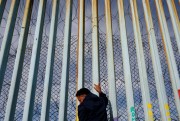 A man holds on to the barrier at the U.S.-Mexico border, Tijuana, Mexico, Jan. 8, 2019 (AP photo by Gregory Bull).