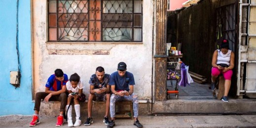 People surf the internet on their smartphones on the sidewalk in Havana, Cuba, Dec. 6, 2018 (AP photo by Desmond Boylan).