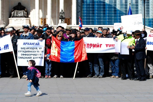 A child walks past Mongolians protesting corruption in Ulaanbaatar, Mongolia, March 31, 2017 (AP photo by Ganbat Namjilsangarav).