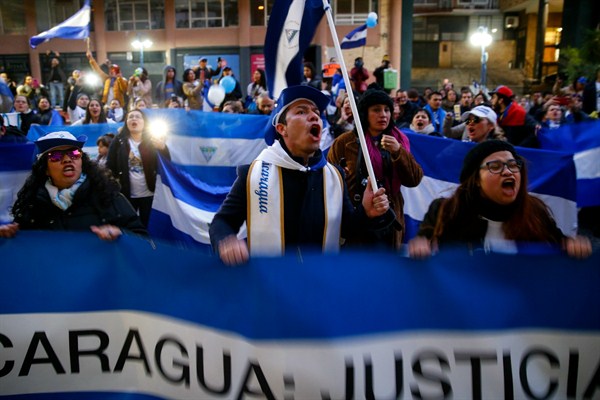 Demonstrators shout slogans and wave Nicaraguan flags during a protest against the Nicaraguan government in front of the Nicaraguan Embassy in Madrid, Spain, Jan. 12, 2019 (AP photo by Andrea Comas).