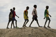 A group of children walk on top of a small hill of dirt in the United Nations protection of civilians site in Bentiu, South Sudan, Dec. 9, 2018 (AP photo by Sam Mednick).