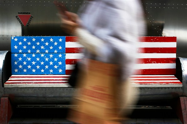 A woman walks by a bench painted with the U.S. flag at a popular shopping mall in Beijing, Jan. 6, 2019 (AP photo by Andy Wong).