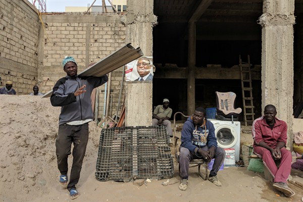 Builders gather around a campaign poster of Senegalese President Macky Sall, who is running for re-election, in Ngor village, near the capital, Dakar, Feb. 20, 2019 (Photo by Anna Pujol-Mazzini).
