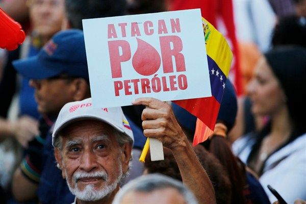A man holds a sign that reads in Spanish “They attack for oil” during a march in support of the state-run oil company PDVSA, in Caracas, Venezuela, Jan. 31, 2019 (AP photo by Ariana Cubillos).