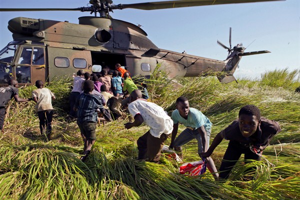 Residents make off with bags of rice in a scramble for food delivered by a South African Air Force helicopter in Nyamatande Village, Mozambique, March 26, 2019 (AP photo by Phill Magakoe).