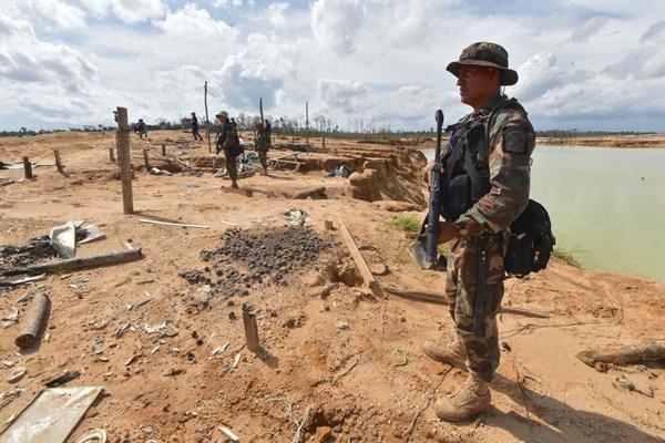 Peruvian police officers stand guard in a recovered area deforested by illegal gold mining in the Madre de Dios province of Peru, Feb. 19, 2019 (pool photo by Cris Bouroncle via AP Images).