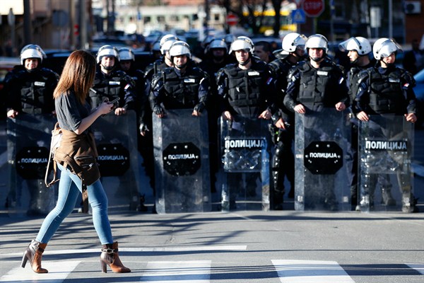 A woman walks in front of a police cordon in front of the police headquarters in Belgrade, Serbia, March 17, 2019 (AP photo by Darko Vojinovic).