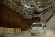 A U.S. Customs and Border Protection agent patrols on the U.S. side of a razor-wire-covered border wall that separates Nogales, Mexico from Nogales, Ariz., March 2, 2019 (AP photo by Charlie Riedel).