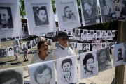 A man and a woman look at images of people who have been disappeared in the context of Mexico’s fight against drug cartels and organized crime, Mexico City, May 10, 2019 (AP photo by Eduardo Verdugo).