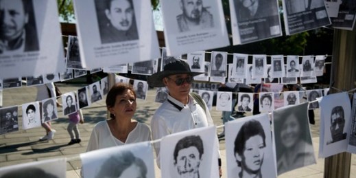 A man and a woman look at images of people who have been disappeared in the context of Mexico’s fight against drug cartels and organized crime, Mexico City, May 10, 2019 (AP photo by Eduardo Verdugo).
