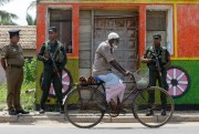 A man rides past soldiers securing a Muslim neighborhood following overnight clashes, Negombo, Sri Lanka, May 6, 2019 (AP photo by Eranga Jayawardena).