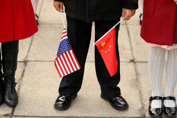 A person holds Chinese and American flags at a welcome ceremony with President Donald Trump and Chinese President Xi Jinping at the Great Hall of the People, Beijing, Nov. 9, 2017 (AP photo by Andrew Harnik).