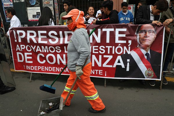 A street cleaner walks past a poster promoting Peruvian President Martin Vizcarra and his proposed reforms aimed at tackling corruption, in Lima, Peru, June 4, 2019 (AP photo by Martin Mejia).