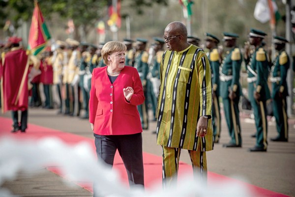 German Chancellor Angela Merkel is greeted with military honors by Burkina Faso’s president, Roch Kabore, at the Presidential Palace, Ouagadougou, May 1, 2019 (Photo by Michael Kappeler for dpa via AP Images).
