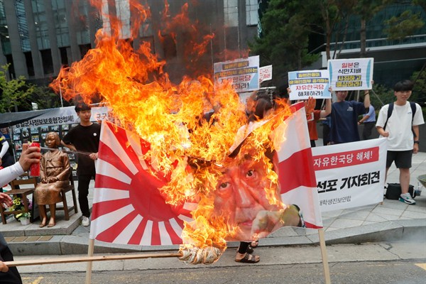 South Korean students burn a banner of a Japanese rising sun flag and Japanese Prime Minister Shinzo Abe during a rally denouncing the Japanese government’s trade restrictions, Seoul, July 29, 2019 (AP photo by Ahn Young-joon).