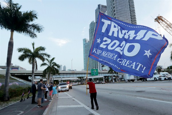 A supporter of President Donald Trump carries a flag outside of the venue for the Democratic presidential primary debate, in Miami, June 26, 2019 (AP photo by Lynne Sladky).