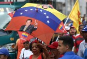 A supporter of Venezuelan President Nicolas Maduro wears a parasol in the colors of the Venezuelan flag and with the picture of the late Hugo Chavez, at a pro-government rally in Caracas, May 20, 2019 (DPA photo by Pedro Mattey via AP).