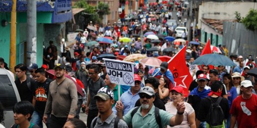 At a protest against President Juan Orlando Hernandez, a sign reads “Resign JOH” in Spanish, Tegucigalpa, Honduras, Aug. 6, 2019 (AP photo by Elmer Martinez).