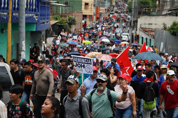 At a protest against President Juan Orlando Hernandez, a sign reads “Resign JOH” in Spanish, Tegucigalpa, Honduras, Aug. 6, 2019 (AP photo by Elmer Martinez).