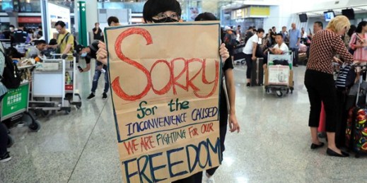 A protester shows a sign to stranded travelers during a demonstration at the airport in Hong Kong, Aug. 13, 2019 (AP photo by Kin Cheung).