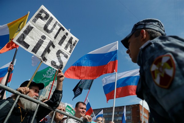 Demonstrators with Russian and various political party flags stand in front of a police line during a protest in Moscow, July 20, 2019 (AP photo by Pavel Golovkin).