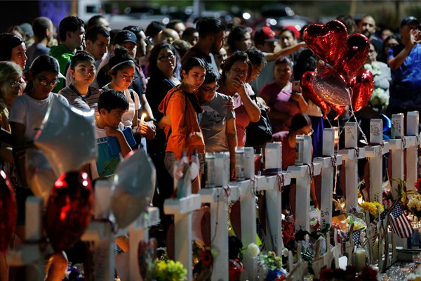 People crowd around a makeshift memorial near the site of a mass shooting in El Paso, Texas, Aug. 5, 2019 (AP photo by John Locher).