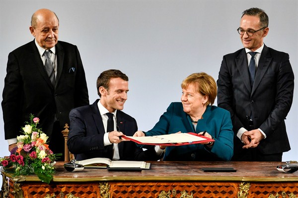 German Chancellor Angela Merkel and French President Emmanuel Macron exchange contracts alongside their respective foreign minsters, in Aachen, Germany, Jan. 22, 2019 (AP photo by Martin Meissner).
