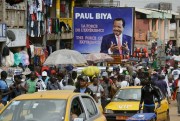 Pedestrians walk past an election campaign billboard of Cameroon’s president, Paul Biya, at Mokolo Market in Yaounde, Cameroon, Oct. 11, 2018 (AP photo by Sunday Alamba).