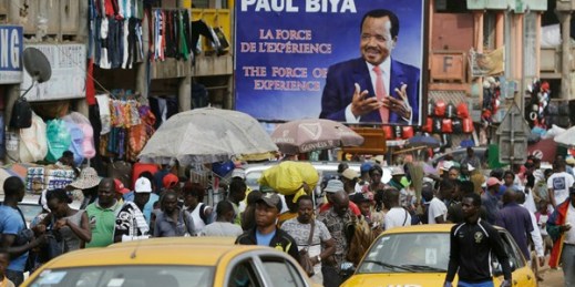Pedestrians walk past an election campaign billboard of Cameroon’s president, Paul Biya, at Mokolo Market in Yaounde, Cameroon, Oct. 11, 2018 (AP photo by Sunday Alamba).