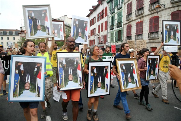 Demonstrators hold upside down portraits of French President Emmanuel Macron during a protest through the streets of Bayonne, France, Aug. 25, 2019 (AP photo by Bob Edme).