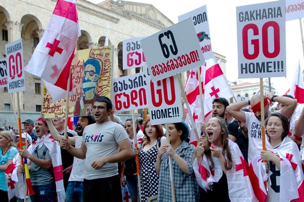 Opposition demonstrators hold Georgian flags and posters reading “Georgian Interior Minister Giorgi Gakharia go home” during a rally in front of the Georgian Parliament’s building in Tbilisi, Georgia, July 6, 2019 (AP photo by Shakh Aivazov).