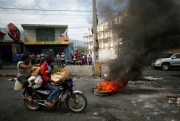 A motorcyclist drives past a burning barricade amid anti-government protests, in Port-au-Prince, Haiti, Sept. 30, 2019 (AP photo by Rebecca Blackwell).