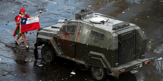 A protester faces off with an armored police vehicle during an anti-government march in Santiago, Chile, Oct. 22, 2019 (AP photo by Esteban Felix).