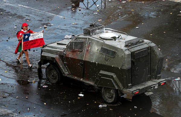 A protester faces off with an armored police vehicle during an anti-government march in Santiago, Chile, Oct. 22, 2019 (AP photo by Esteban Felix).