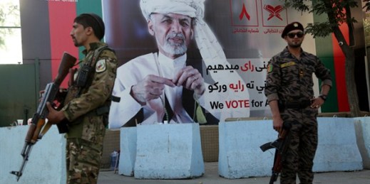 Afghan security forces stand guard in front of an election poster for President Ashraf Ghani in Kabul, Afghanistan, Sept. 23, 2019 (AP photo by Rahmat Gul).