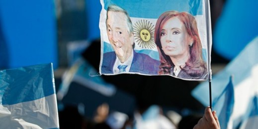 A supporter of Cristina Fernandez and her late husband Nestor Kirchner holds up a flag featuring their portraits during a campaign rally for the leading opposition ticket, in Santa Rosa, Argentina, Oct. 17, 2019. (AP photo by Natacha Pisarenko).