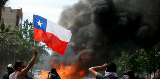 An anti-government protester waves a Chilean flag during clashes with police amid a general strike in Santiago, Chile, Oct. 23, 2019 (AP photo by Luis Hidalgo).