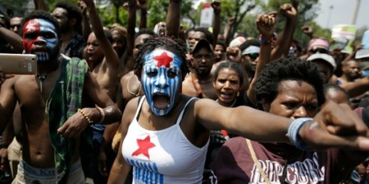 A Papuan activist with her face painted with the colors of the separatist Morning Star flag during a rally near the presidential palace, Jakarta, Indonesia, Aug. 22, 2019 (AP photo by Dita Alangkara).