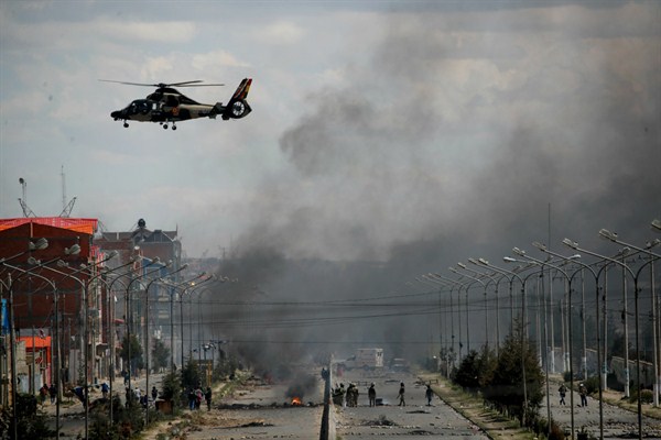 A Bolivian army helicopter flies over the road leading to the state-owned Senkata gasoline plant, El Alto, Bolivia, Nov. 19, 2019 (AP photo by Natacha Pisarenko).
