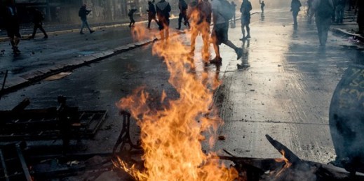 Anti-government protesters walk past a burning barricade set on fire during clashes with police in Santiago, Chile, Oct. 29, 2019 (AP photo by Rodrigo Abd).