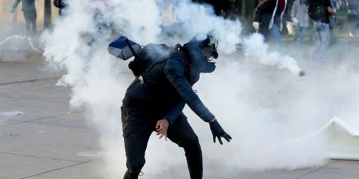 A student throws a tear gas canister back at police during clashes at the National University in Bogota, Colombia, Nov. 26, 2019 (AP photo by Ivan Valencia).